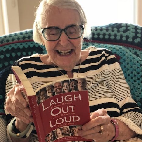woman laughing while reading a book
