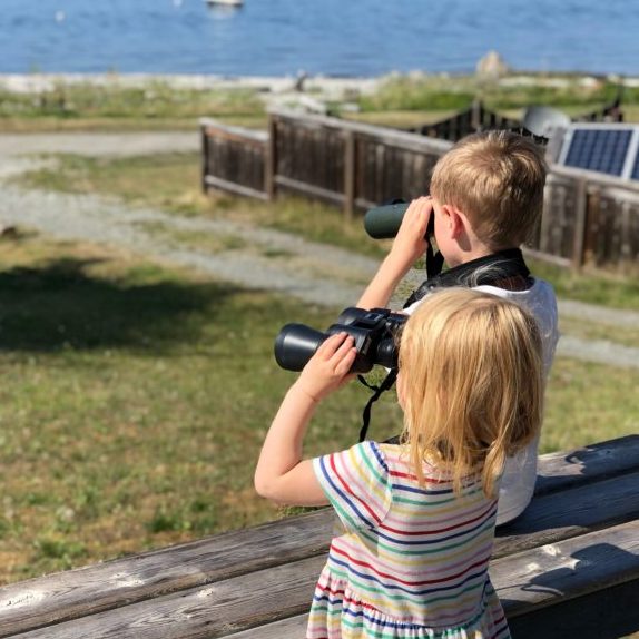 two children looking out to sea with binoculars
