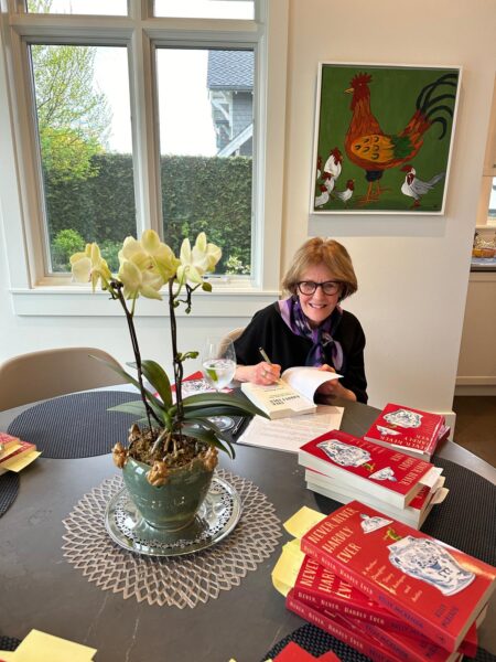 Woman signing pile of books