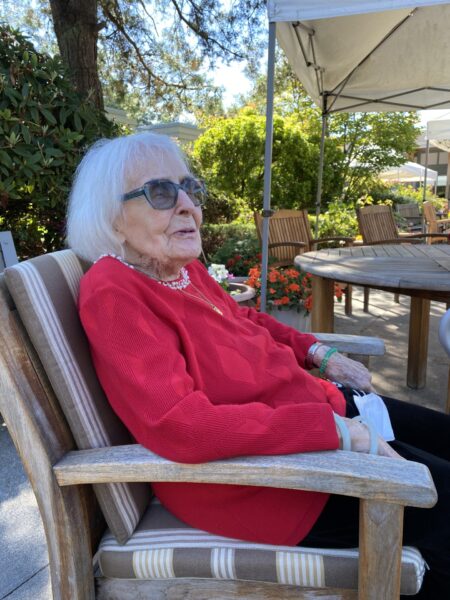 elderly woman in red shirt sitting in a chair