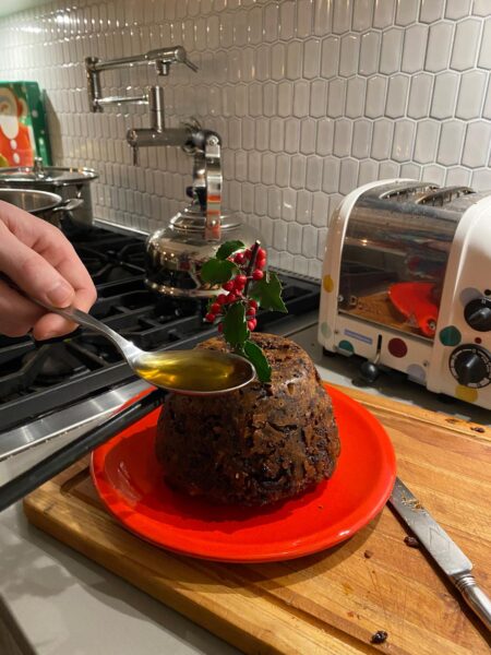 Spoon of rum being poured onto Christmas pudding